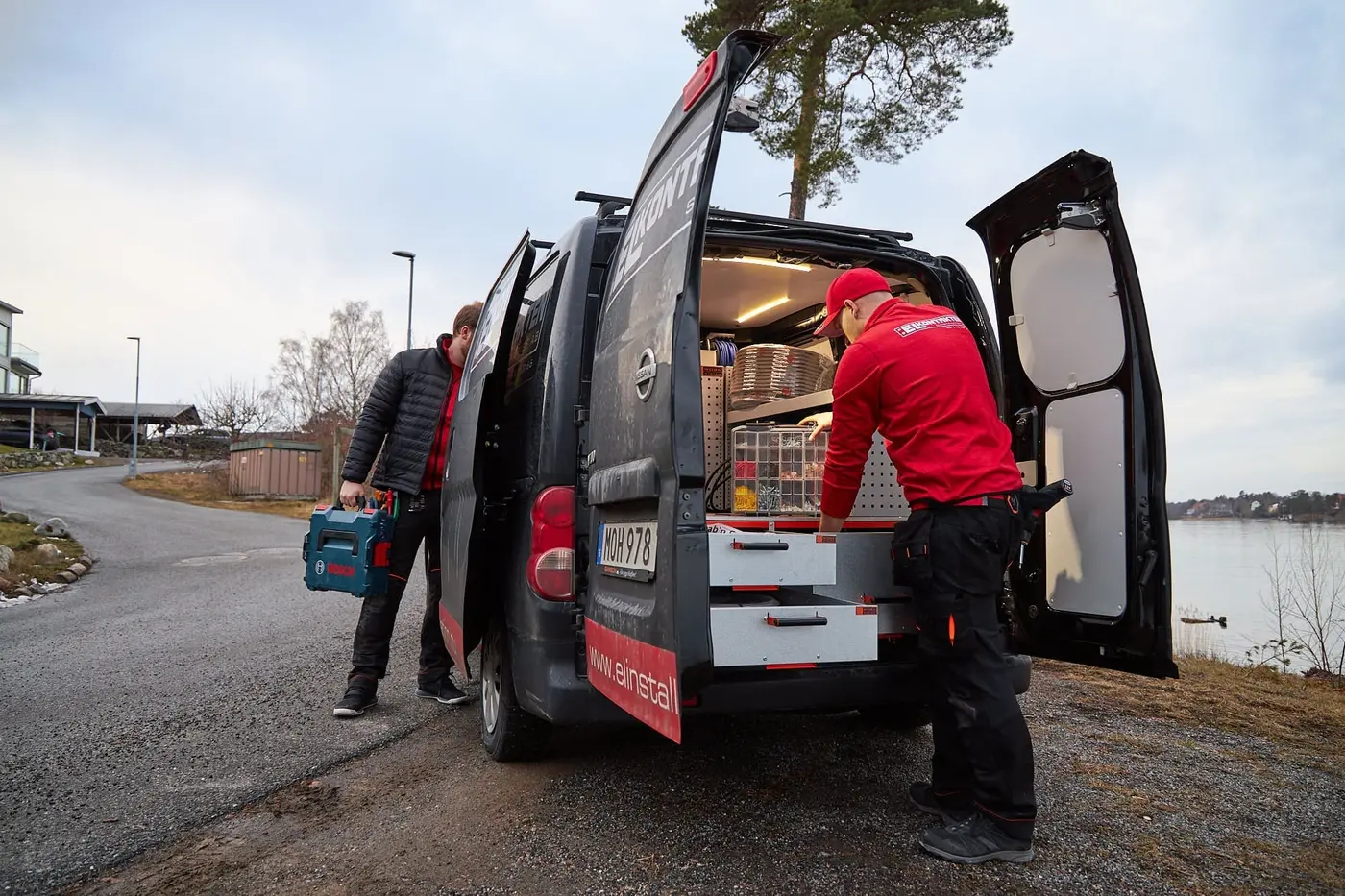 Elektriker vid den märkta servicebilen med verktygslåda